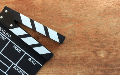 closeup movie clapper board on wood table with soft-focus and over light in the background