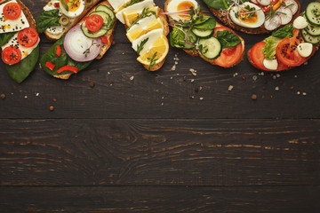 Variety of healthy vegetarian sandwiches on dark wood, top view