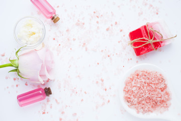 Spa and natural cosmetics concept. Set of sea salt, rose, natural clay ,shea oil, glass bottles and other spa treatment tools on the white background. Top view. Space for a text. Close up.