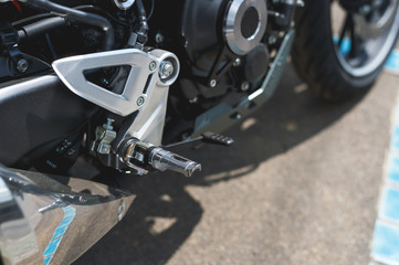 closeup right footpeg with brake pedal of sport motorcycle with soft-focus and over light in the background