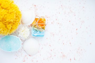 Spa and natural cosmetics concept. Set of skin and body care tools: shea oil, seashells, sponges, soap, clay and seaweed on the white background. Top view. Close up.