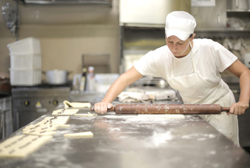 Pastry chef using a rolling pin on cake dough