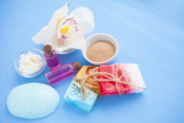 Spa and natural cosmetics concept. Set of sea salt, orchid, natural clay ,shea oil, glass bottles and other spa treatment tools on the blue wooden background. Top view. Space for a text. Close up.