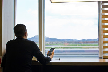 A man with a smartphone waiting for the plane, flight at the airport