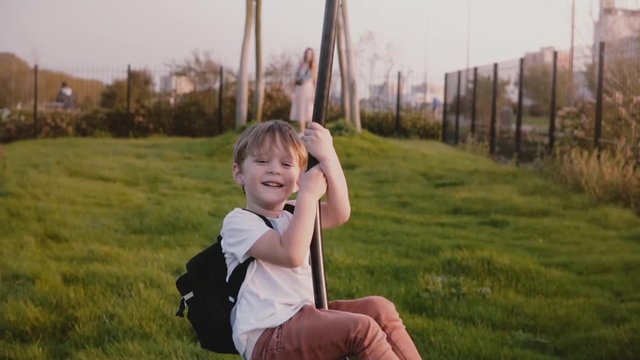 Little European boy on a city park zipline. Excited happy male kid rides long zip wire smiling. Front view. Childhood.