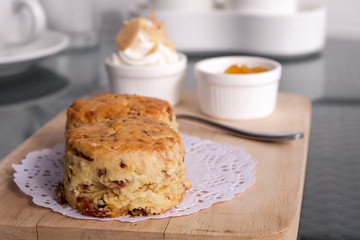 Traditional delicious British pastry and desert - scones eated with cream and jame, on a wooden board.