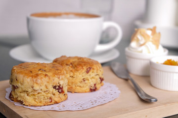 Traditional delicious British pastry and dessert - eating scones with hot latte coffee.