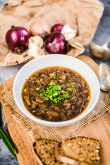 Homemade healthy french onion soup with plain toasted some bread top down view, on rustic wooden table.