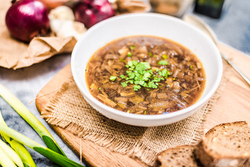 Homemade healthy french onion soup with plain toasted some bread top down view, on rustic wooden table.