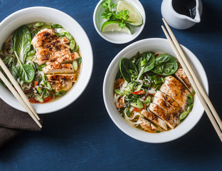 Chicken, noodles and vegetables asian style soup on a blue background, top view
