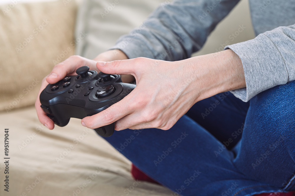 Wall mural man holding a joystick controllers while playing a video games at home