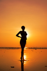 Silhouette of a young and fit woman on the beach at sunset