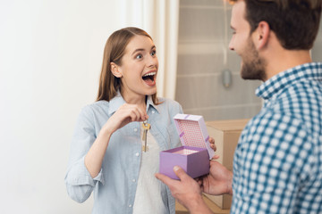 The guy gives his girl a box with a gift. The girl received a gift the key to new housing.