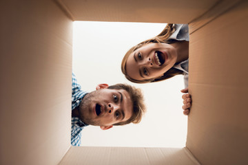 The girl and the boy are looking at the empty box. View from inside the box close-up.