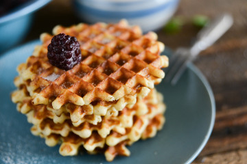 Dessert: round waffles with fresh berries blackberries and icing sugar on a wooden background.