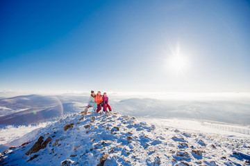 Group of gay girlfriend girls sit on top of mountain and drink tea. Rest after skiing on snowboard. Winter