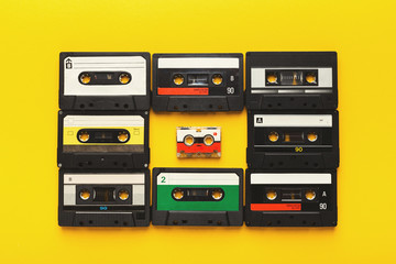 Big retro cassettes framing a small one on yellow background, top view, copy space
