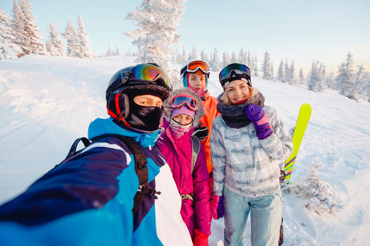 Team of friends makes a selfie photo of herself with snowboards and skis. action camera.