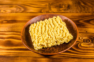 Ceramic plate with instant noodles on wooden table