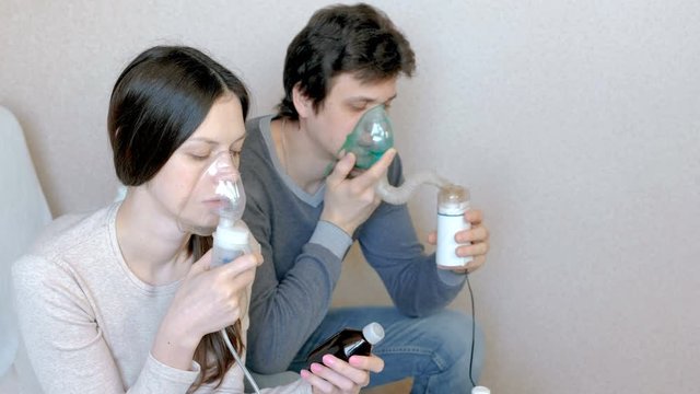 Use nebulizer and inhaler for the treatment. Man and woman inhaling through inhaler mask. Front view.