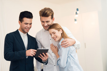 Young couple in a meeting with a realtor. Guy and girl make a contract with realtor buying property.