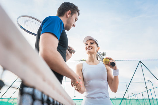 Tennis player man and woman giving handshake after match at the net