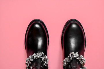Fashionable female black boots with rhinestones-crystals and on a metal chain on a pink background. The concept of fashion. Top view. Flat lay.