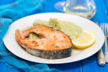 fried salmon with spinach puree and lemon on white plate