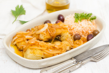 fried cod fish with olives, onion and boiled rice on dish