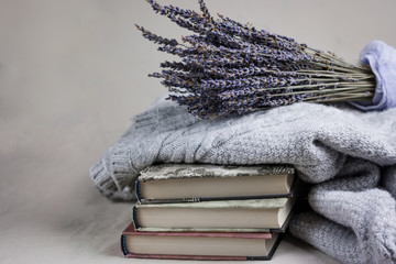 gray cozy knitted sweaters and lavender on a heap books