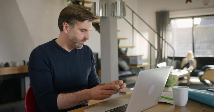Handsome Man at Home sitting at Table throwing away Note on sticky memo