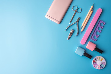 A set of cosmetic tools for manicure and pedicure on a blue background. Gel polishes, nail files...