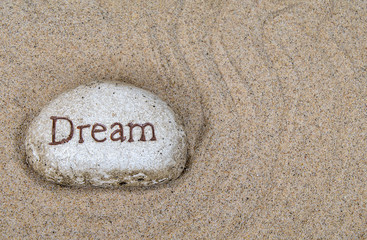 Fototapeta na wymiar close up of stone with dream sign in raked beach sand pattern