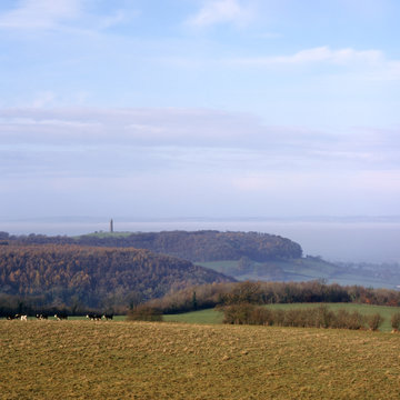 View towards the Tynedale Monument on the edge of the Cotswold Hills escarpment near Wotton Under Edge, Gloucesteshire, UK. The Severn Vale beyond is filled with low lying mist.
