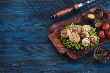 Grilled mushrooms champignons with vegetable on a blue wooden background