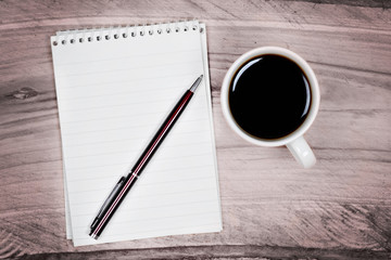 Blank notepad with pen and coffee cup on table