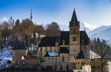 Fototapeta na wymiar Close up of the St. Oswald fortified church with snow covered mountains in the background