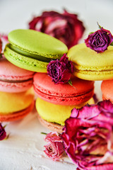 Dessert: A Delicate Fresh Colorful French Macaroons In Pastel Colors With Flowers Roses On A Light Textile Background, Top View