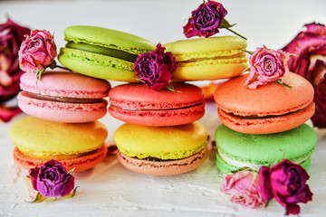Obraz na płótnie Canvas Dessert: A Delicate Fresh Colorful French Macaroons In Pastel Colors With Flowers Roses On A Light Textile Background, Top View