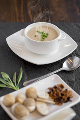 Mushroom cream soup with herbs and spices in white bowl