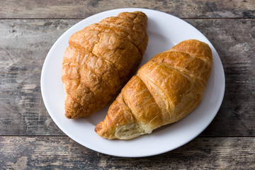 Croissant in plate on wooden table. 