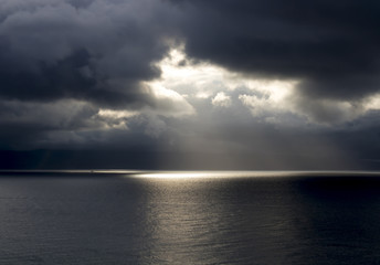 Sun Breaks Through Dark Clouds Over Ocean - 195190296