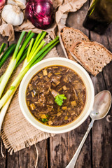 Homemade healthy french onion soup with plain toasted some bread top down view, on rustic wooden table.