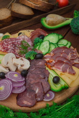 Cold smoked meat with prosciutto, salami, bacon, pork chops, cheese, mushrooms, cucumber, bread, avocado, onion and olives. Wooden rustic background. Top view