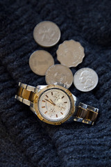 Women's watch with few coins of dollars on wool
