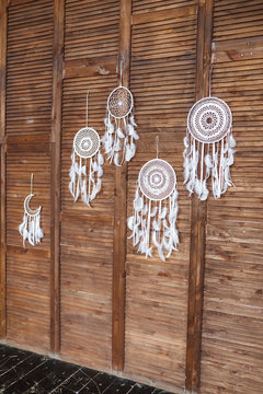Many Handmade white dream catchers hanging at wooden wall
