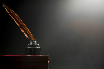 Knowledge concept, pen in the inkwell on a pile of books