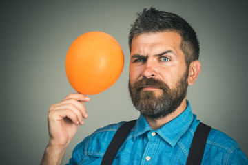 Happy birthday, celebration concept - father with orange balloon. Stylish man with beard and mustache in blue denim shirt holds balloon. Handsome bearded man holds air balloon in hands. Copy space - Powered by Adobe