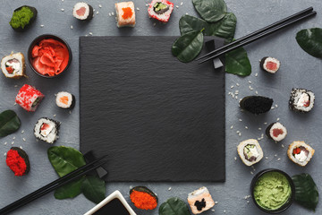 Square black slate with sushi on grey background