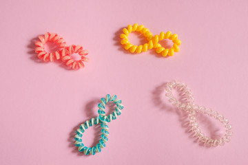 Colorful hair bands in the form of number 8 on pink background. Place for text, design, pattern.